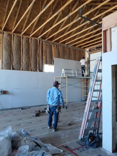 Two crew members hanging drywall